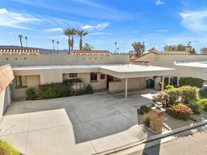 A residential building with a flat roof, multiple windows, and a paved courtyard. - Bright Golf View Villa: Vaulted Ceilings, Patio Dining, Mtn Views & Resort Pool (Palm Desert)
