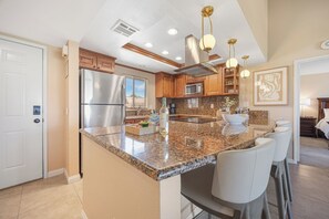 A modern kitchen with granite countertops, stainless steel appliances, and a central island with bar seating. - Bright Golf View Villa: Vaulted Ceilings, Patio Dining, Mtn Views & Resort Pool (Palm Desert)