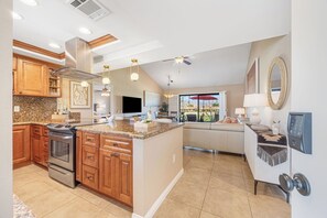 A modern kitchen with granite countertops, wooden cabinets, and a built-in oven. - Bright Golf View Villa: Vaulted Ceilings, Patio Dining, Mtn Views & Resort Pool (Palm Desert)