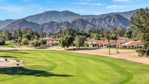 A golf course with a mountain backdrop, surrounded by residential buildings. - Bright Golf View Villa: Vaulted Ceilings, Patio Dining, Mtn Views & Resort Pool (Palm Desert)