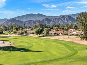 A golf course with a mountain backdrop, surrounded by residential buildings. - Bright Golf View Villa: Vaulted Ceilings, Patio Dining, Mtn Views & Resort Pool (Palm Desert)