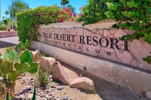 Schild für den Palm Desert Resort Country Club mit Wüstenlandschaft und Kakteen.