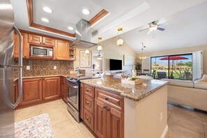 A modern kitchen with granite countertops, stainless steel appliances, wooden cabinets, and a large island. - Bright Golf View Villa: Vaulted Ceilings, Patio Dining, Mtn Views & Resort Pool (Palm Desert)