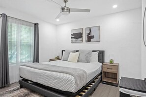 A bedroom with a bed, bedside tables, a ceiling fan, and artwork on the wall. - Spacious 4-bedroom home in South Austin with a private enclosed backyard space (Austin)