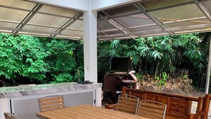 An outdoor dining area with a wooden table and metal chairs, surrounded by a covered patio with a view of lush greenery. - A cozy private space in Cuenca Batangas, perfect for relaxing getaways! (Cuenca)