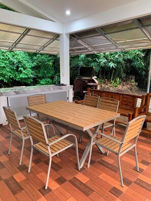 An outdoor dining area with a wooden table and metal chairs, surrounded by a covered patio with a view of lush greenery. - A cozy private space in Cuenca Batangas, perfect for relaxing getaways! (Cuenca)