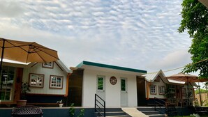 A building with a central entrance, two side wings, and a covered outdoor seating area. - A cozy private space in Cuenca Batangas, perfect for relaxing getaways! (Cuenca)