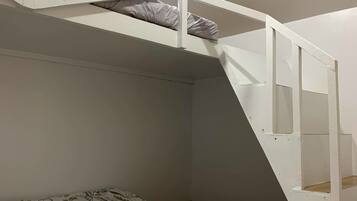 Un lit superposé avec une échelle, un lit inférieur recouvert d’une courtepointe à motifs floraux et un plafond blanc.
