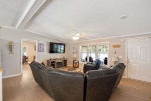 Un salon avec une cheminée, un téléviseur et un ventilateur de plafond.