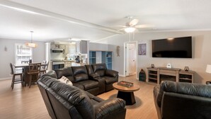 A modern living room with a leather sofa, a coffee table, and a flat-screen TV mounted on the wall. - Lake it Easy Private Dock with fish cleaning station (Batesburg-Leesville)