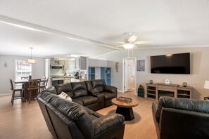 Ein modernes Wohnzimmer mit einer Ledersofa, einem Couchtisch und einem flachbildfernseher an der Wand.