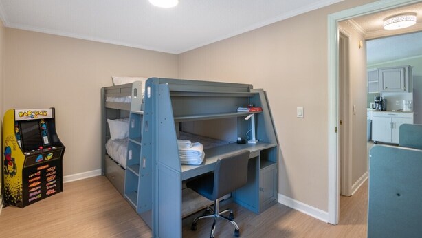 A bunk bed with a desk and chair, a Pac-Man arcade game, and a kitchenette in the background. - Lake it Easy Private Dock with fish cleaning station (Batesburg-Leesville)