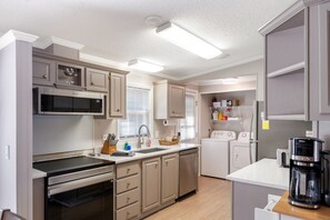 A compact kitchen with built-in appliances, a microwave, oven, and a coffee maker. - Lake it Easy Private Dock with fish cleaning station (Batesburg-Leesville)