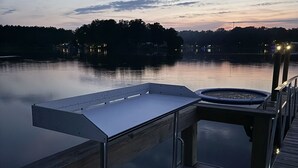 A wooden dock extending over calm water with a hot tub and a metal bench. - Lake it Easy Private Dock with fish cleaning station (Batesburg-Leesville)
