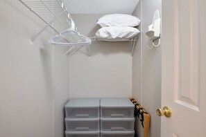 Un placard de rangement avec des tiroirs en plastique, une tringle pour suspendre les vêtements et un radiateur blanc fixé au mur.