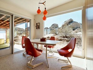 Ein modernes Interieur mit Essbereich, roten Stühlen, einem Tisch und Blick auf felsiges Gelände.