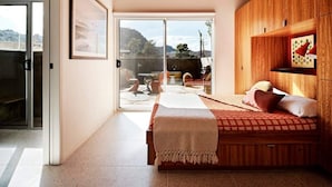 A bedroom with a bed, wooden ceiling, a sliding glass door to a patio, and a framed picture on the wall. - Radziner Modernist Cabin By Homestead Modern (Joshua Tree)