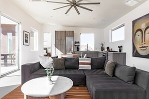 A modern living room with a sectional sofa, a round coffee table, and a ceiling fan. - Shelter 2 By Homestead Modern (Joshua Tree)