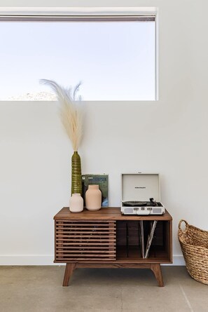Een houten console tafel met een platenspeler, een vaas met veertjes en een boek.