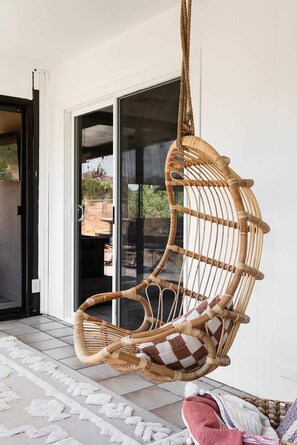 A wicker hanging chair with a checkered cushion on a tiled porch. - Sommer Ranch By Homestead Modern (Yucca Valley)