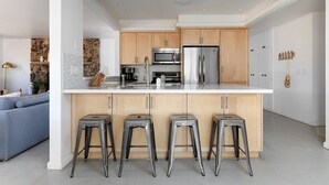 A modern kitchen with a central island, stainless steel appliances, and wooden cabinets. - Sommer Ranch By Homestead Modern (Yucca Valley)