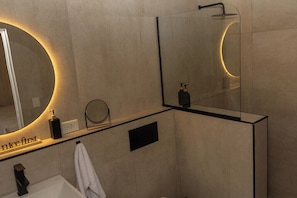 A modern bathroom with a large mirror, a sink, and a shower. - Iuman Patagonia (El Calafate)