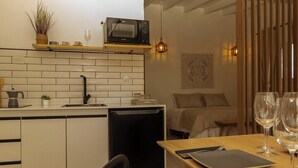 A compact kitchen with a microwave, sink, and small refrigerator. There is a dining area with a table, chairs, and wine glasses. - Iuman Patagonia (El Calafate)