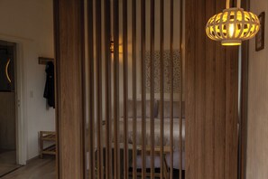 A room with a bed, a standing lamp, and a wooden partition. - Iuman Patagonia (El Calafate)