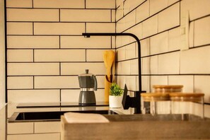 A kitchen with a brick backsplash, a coffee maker on the counter, a wooden spoon, and a potted plant. - Iuman Patagonia (El Calafate)