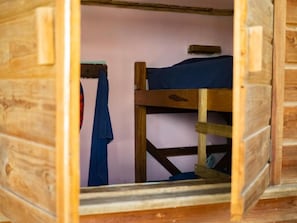 Une chambre avec un lit superposé en bois, avec un lit simple en haut et un lit en bas.
