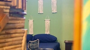 A room with a bed, a chair, and macramé wall hangings. - Hostel Bocas Estrella (Bocas del Toro)