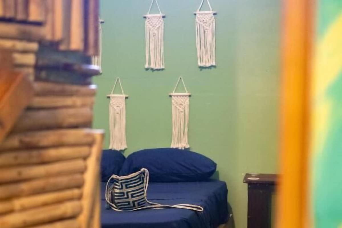 Une pièce comprenant un lit, une chaise et des décorations murales en macramé.