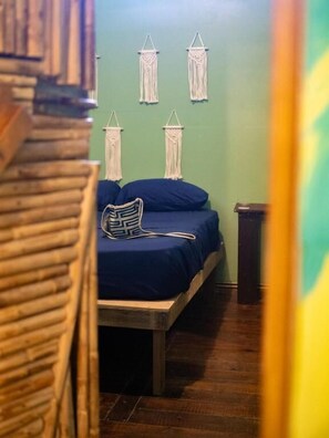 Une pièce comprenant un lit, une chaise et des décorations murales en macramé.