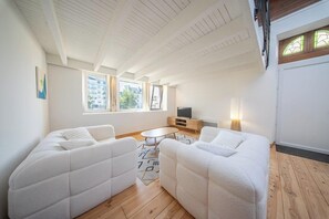 Ein modernes Wohnzimmer mit hoher Decke, einem Flachbildfernseher, einer Sofagarnitur und einem kleinen Couchtisch.