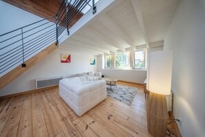 A loft-style room with a sloped ceiling, a white sofa, a small round table, and a floor lamp. - La pépite : écrin historique au bord de l'eau (Quimper)