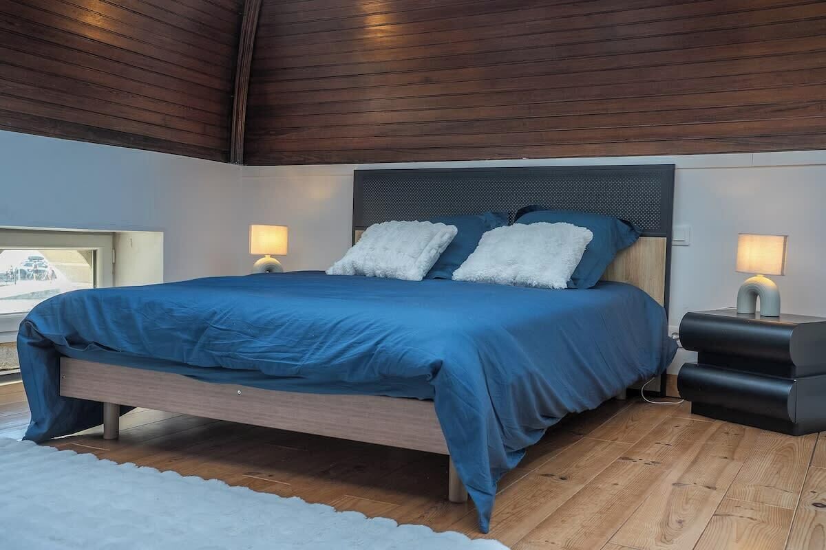 A bedroom with a bed, nightstands, and a view of the outside.
