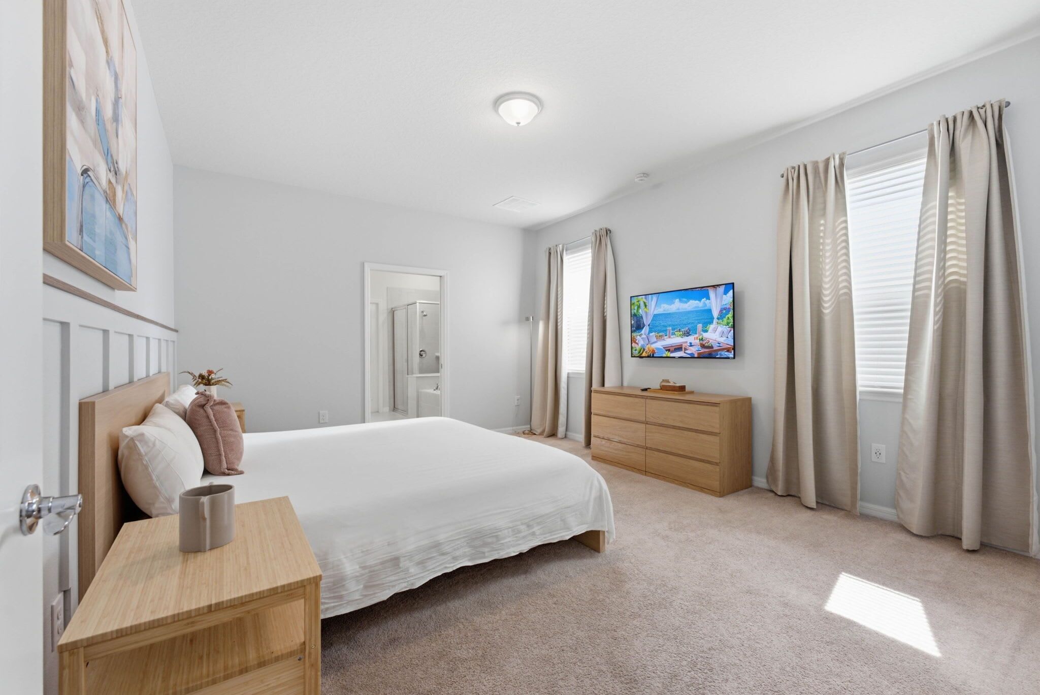 A bedroom with a bed, a dresser, a television, and a window with curtains.