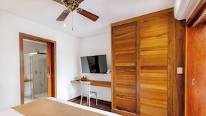 Een slaapkamer met een bed, bureau, stoel, televisie en garderobe.