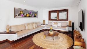 Een moderne woonkamer met een modulaire bank, een ronde salontafel en een groot kunstwerk in een lijst aan de muur.