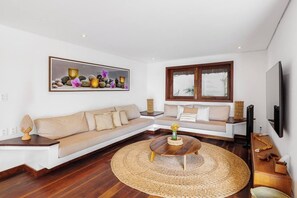 A modern living room with a sectional sofa, a round coffee table, and a large framed artwork on the wall. - Deluxe 2-Bedroom Family Suite at Villa Luz Do Mar (Jijoca de Jericoacoara)