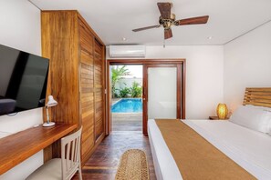 A bedroom with a TV, bedside table, lamp, and a view of an outdoor swimming pool. - Deluxe 2-Bedroom Family Suite at Villa Luz Do Mar (Jijoca de Jericoacoara)