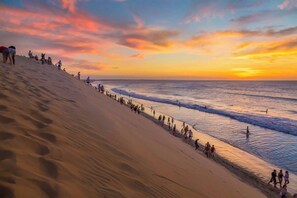 A beach with people walking along the shore and a sunset in the background. - Deluxe 2-Bedroom Family Suite at Villa Luz Do Mar (Jijoca de Jericoacoara)