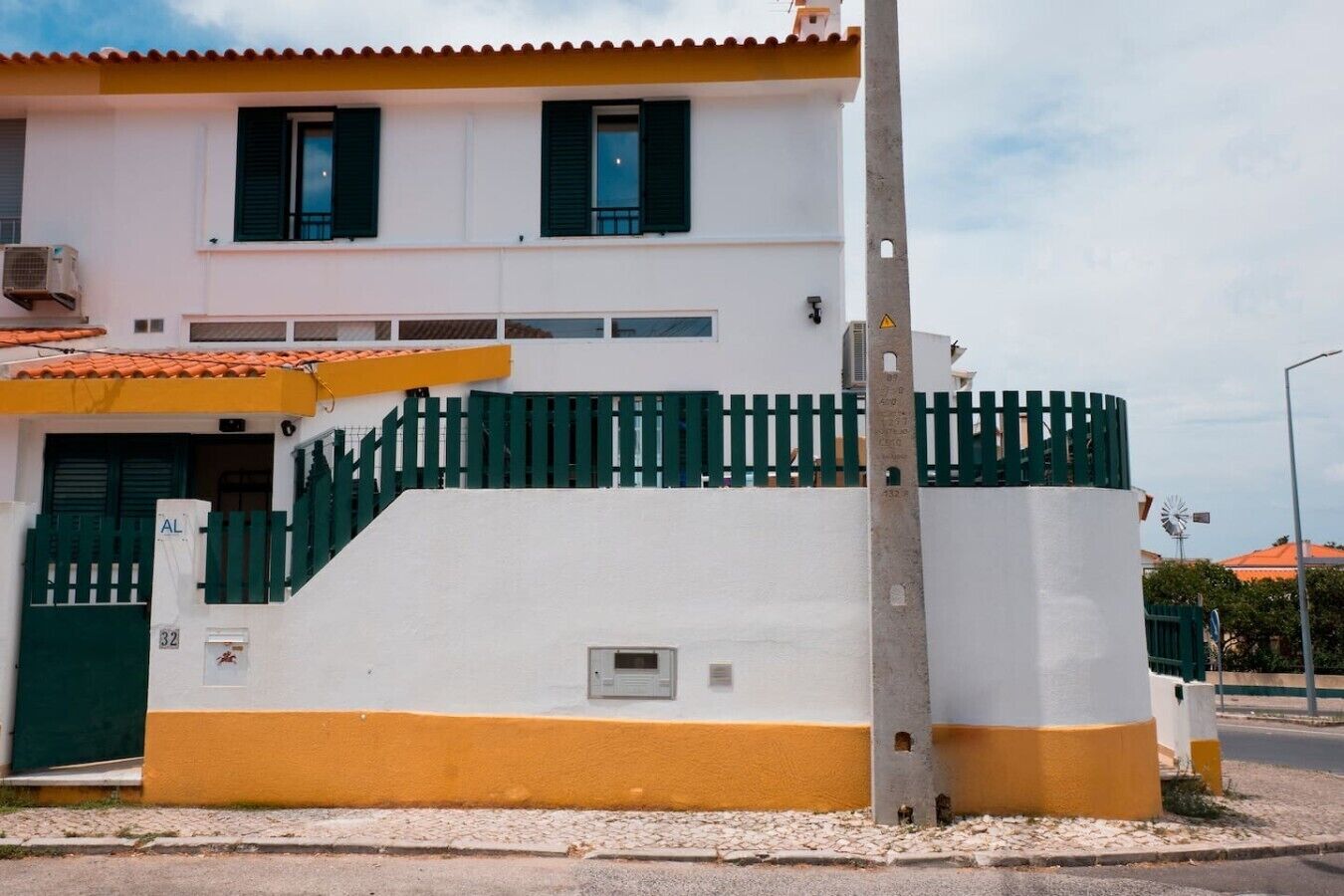 A two-story building with a white facade, green shutters, and a yellow lower section.