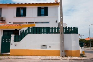 A two-story building with a white facade, green shutters, and a yellow lower section. - Ninho de Setúbal - Studio for solo travelers (S ão Lourenço)