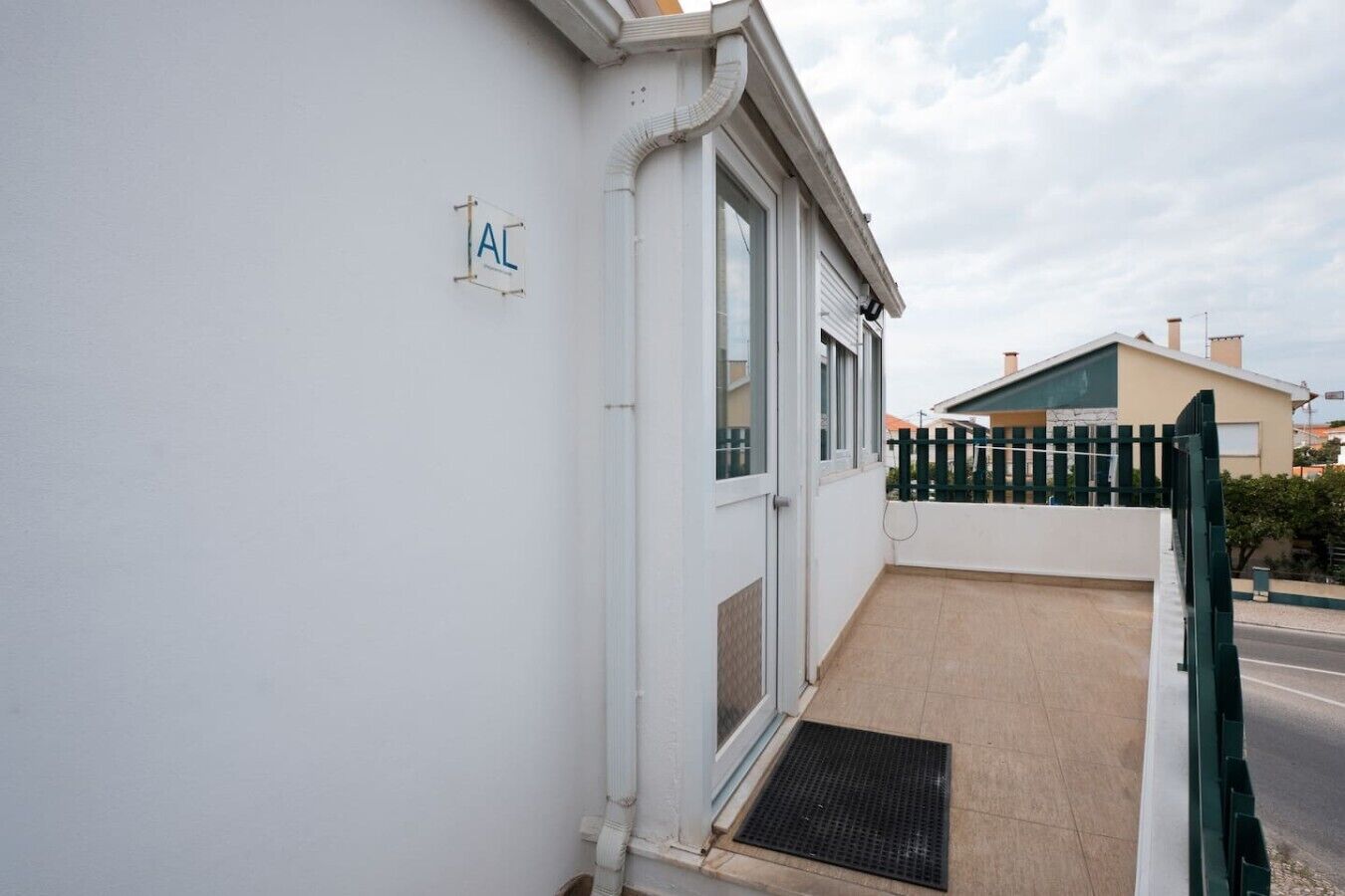 A building with a white exterior, a door, and a small balcony with a metal grate.