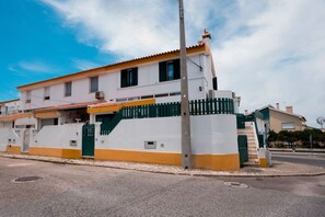 A two-story building with a white and yellow facade, a green fence, and a staircase leading to the upper floor. - Ninho de Setúbal - Studio for solo travelers (São Lourenço)