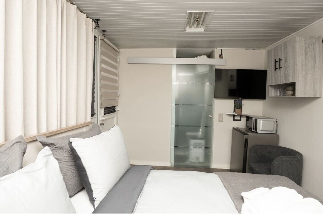 A modern bedroom with a bed, bedside tables, a TV, and a microwave.