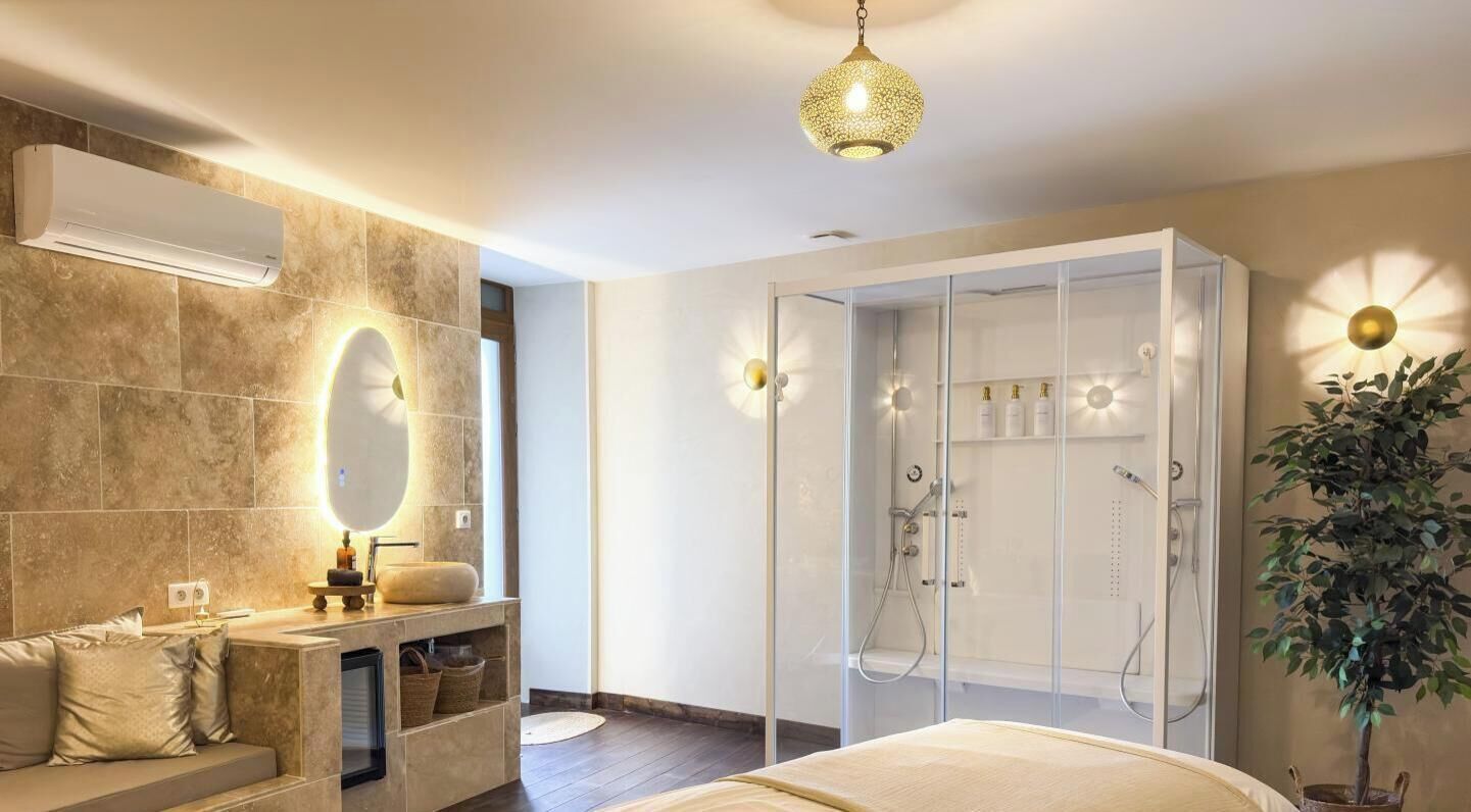 A modern bathroom with a glass-enclosed shower, a vanity with a mirror, and a hanging light fixture.