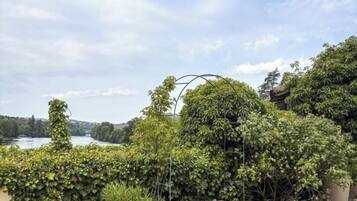 Un jardín con una mesa redonda, una lámpara roja y vista a un lago.