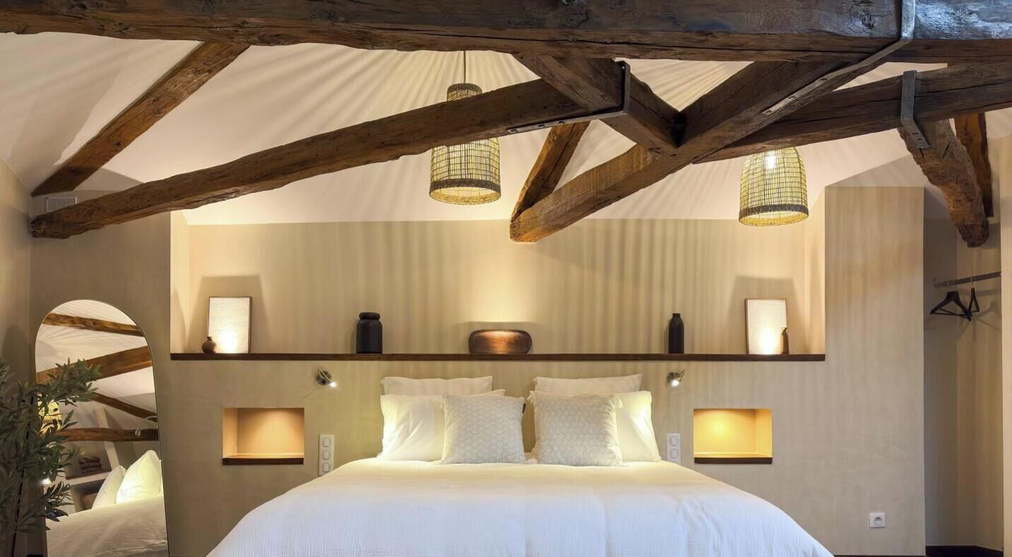 Une chambre à coucher avec un grand lit, des poutres en bois et des luminaires suspendus.